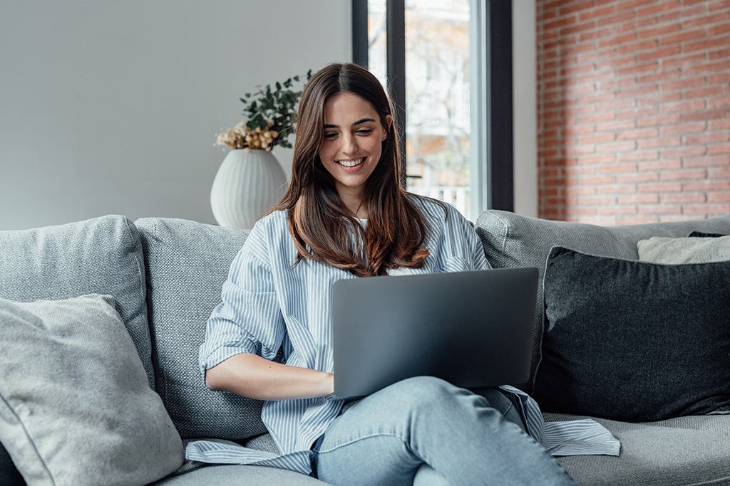 Woman working on a computer while sitting on her couch